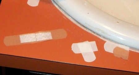 Two band-aid bandages, one with one of the adhesive ends cut off and set on top of the other so that the absobant pad length is doubled for larger wounds