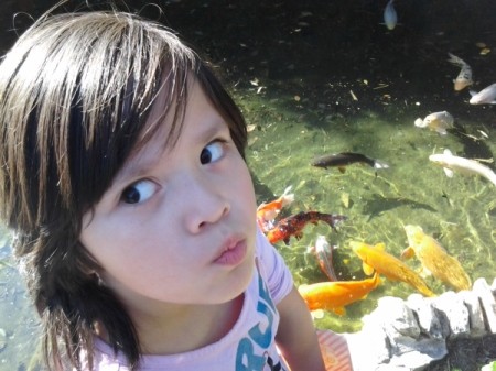 A girl in front of a koi pond at Sunken Gardens, in San Antonio, TX