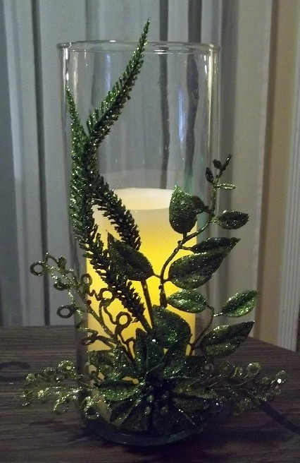 A glass candle holder with greenery.