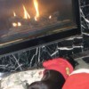 A pug with a red sweater lying in front of fire.