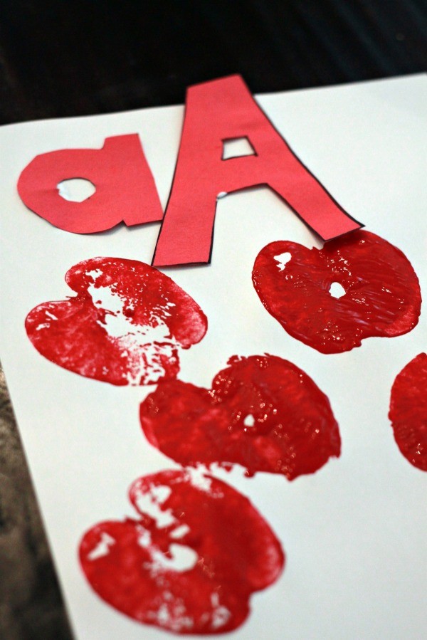 Capital A and Lower Case a on white paper surrounded by stamped apples