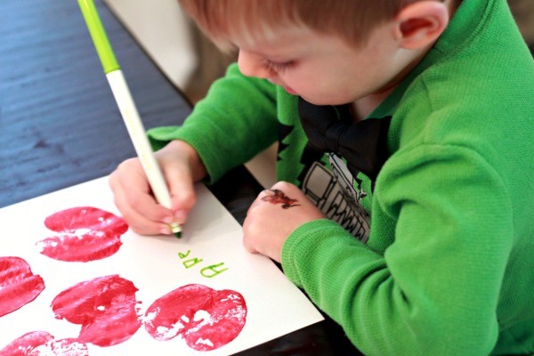 Young boy in green spelling apple