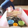 Child playing with dough in large storage bin.