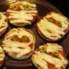English muffin pizzas with strips of cheese and olive eyes.