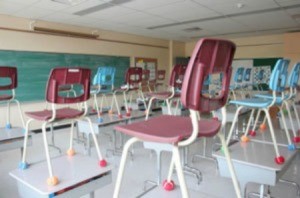 Classroom with chairs on top of desks.