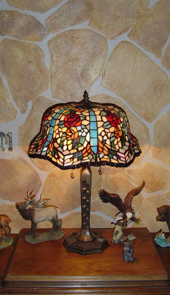 A faux rock wall behind a Tiffany lamp.