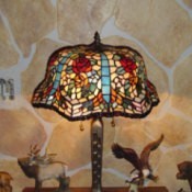 A faux rock wall behind a Tiffany lamp.