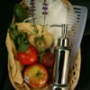 Basket full with apples, a cucumber, herbs, a soap dispenser, loofa, washcloth, and a comb.