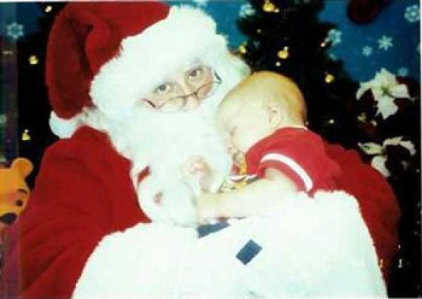 Santa holding a small infant in a red outfit.