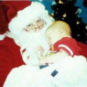 Santa holding a small infant in a red outfit.