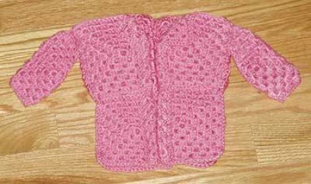 A crocheted doll's sweater in pink.