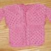 A crocheted doll's sweater in pink.