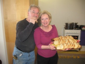 A couple with a tray holding slices of freshly baked bread.
