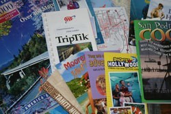 Save Money on Your Next Vacation - a pile of travel brochures.