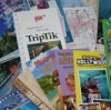 Save Money on Your Next Vacation - a pile of travel brochures.