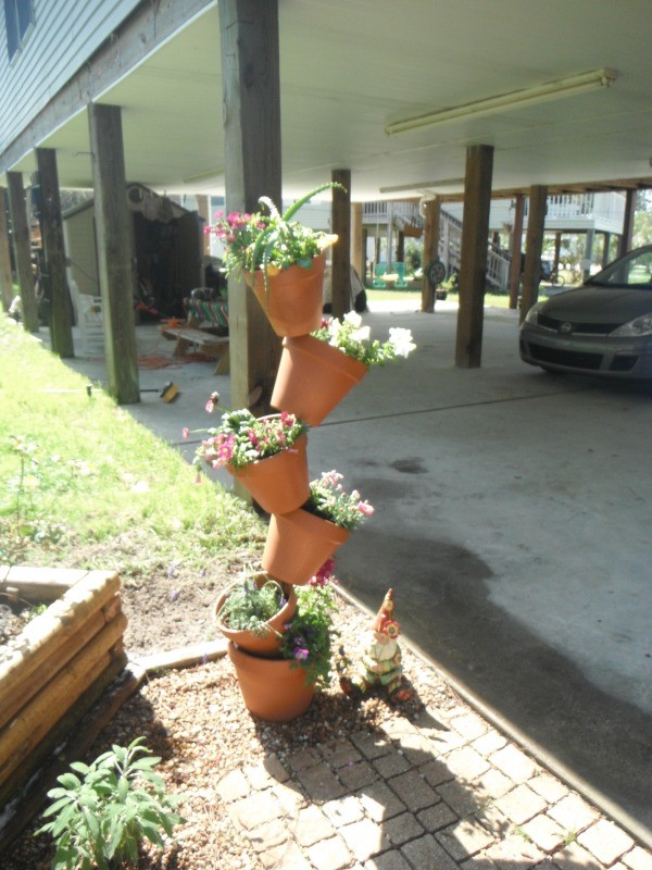 Five terra cotta pots with flowers arranged vertically on rebar.