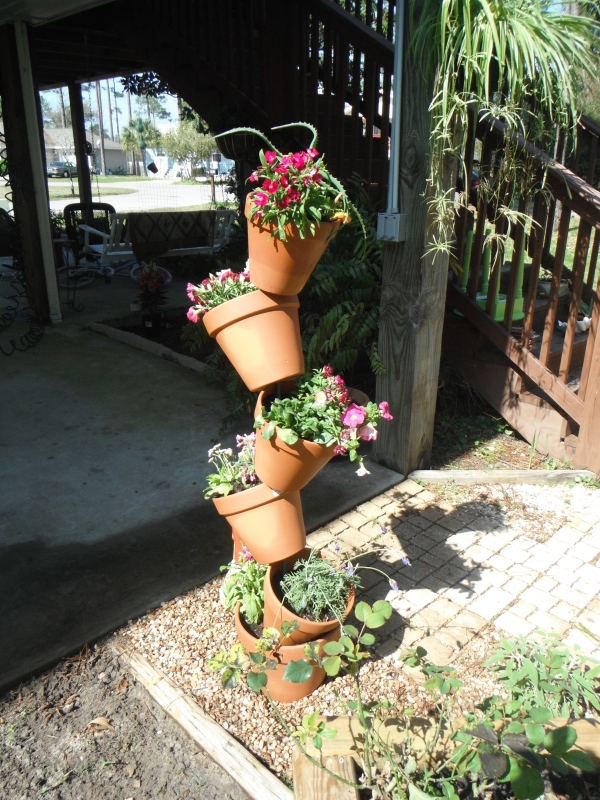 Five terra cotta pots with flowers arranged vertically on rebar.