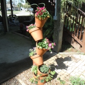 Five terra cotta pots with flowers arranged vertically on rebar.