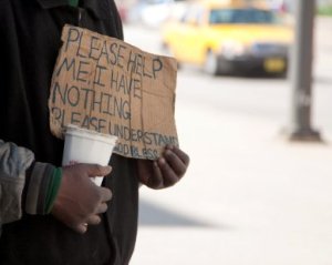 A homeless person holding up a sign