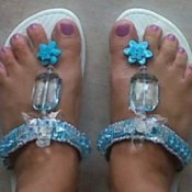 Blue beaded flip flops on woman's feet.