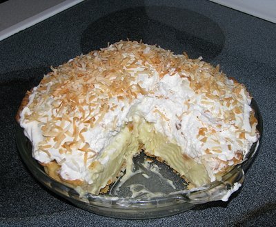 A coconut cream pie with one slice removed.