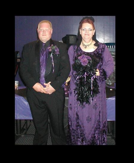 A couple dressed in black and purple formal wear, for a Goth wedding.