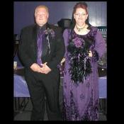 A couple dressed in black and purple formal wear, for a Goth wedding.