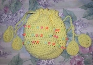 Crochet beaded Easter bag in yellow with pastel beads and egg shapes on ends of drawstrings.
