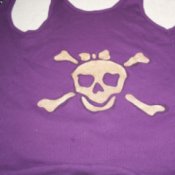 A pirate girl skull painted in gold on a purple tank top.