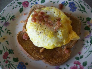 Quick Cheesy Egg On Toast on a plate with bacon bits as a garnish.