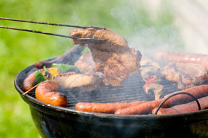 Several types of meats being grilled on a round grill