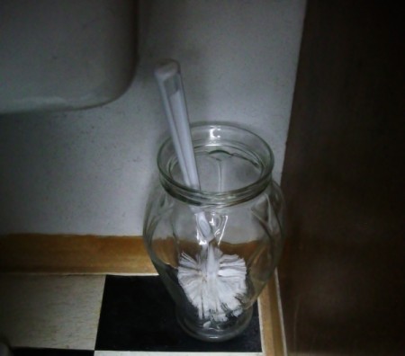 Toilet brush in glass vase.