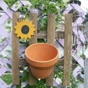 A decoration for you garden that looks like a picket fence with a clay pot on it.
