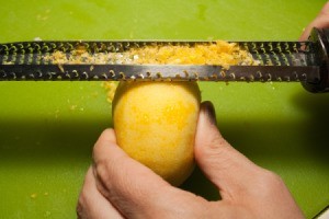 A lemon being zested with a Microplane grater.