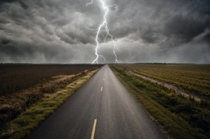 A roadway with storm clouds and lightning in the distance