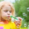 A little girl blowing bubbles.