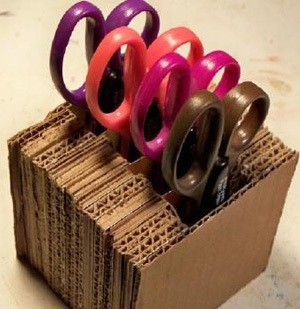 A holder made out of recycled cardboard for scissors or paper edgers.