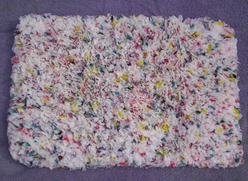Multicolored hooked rug made with shopping bags.