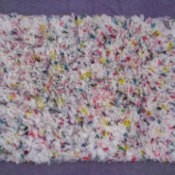 Multicolored hooked rug made with shopping bags.