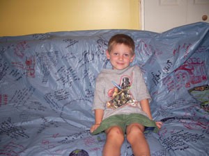 Child sitting on couch covered with keepsake tablecloth.