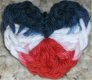 Crochet red, white, and blue heart shaped pin.