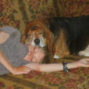 Boy and dog asleep on couch with dog's head resting on the boy's head.