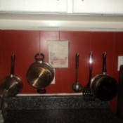 Pots and utensils hanging on kitchen wall.