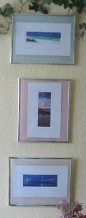 Three frames containing postcards mounted on a wall.