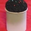 Pincushion made from frosting tub and ball of yarn.