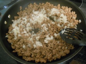 Cooking onion with browned hamburger.