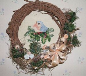 Wreath with cross stitch mounted in center.