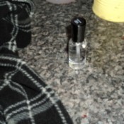 Piece of clothing and bottle of clear nail polish.