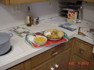 Tray of food on a kitchen counter along with mail, a box of cereal, etc.