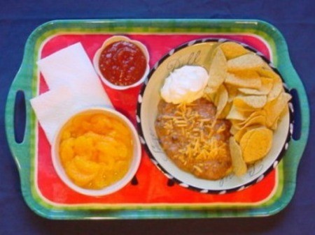 Serving tray with pasta bowl of bean dip, chips, sour cream, and a side of salsa.